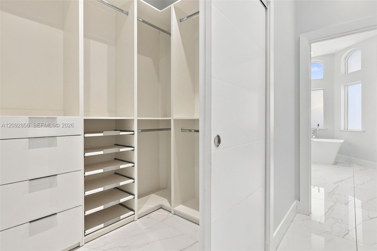 Walk-in closet featuring custom white cabinetry, built-in shelving, multi-level hanging rods, and integrated drawers