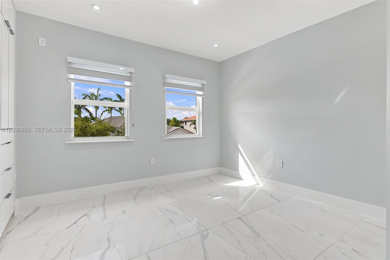4th bedroom - 2nd floor - Neutral-toned interior featuring large-format tile flooring with veining, recessed lighting, and dual windows with roller shades