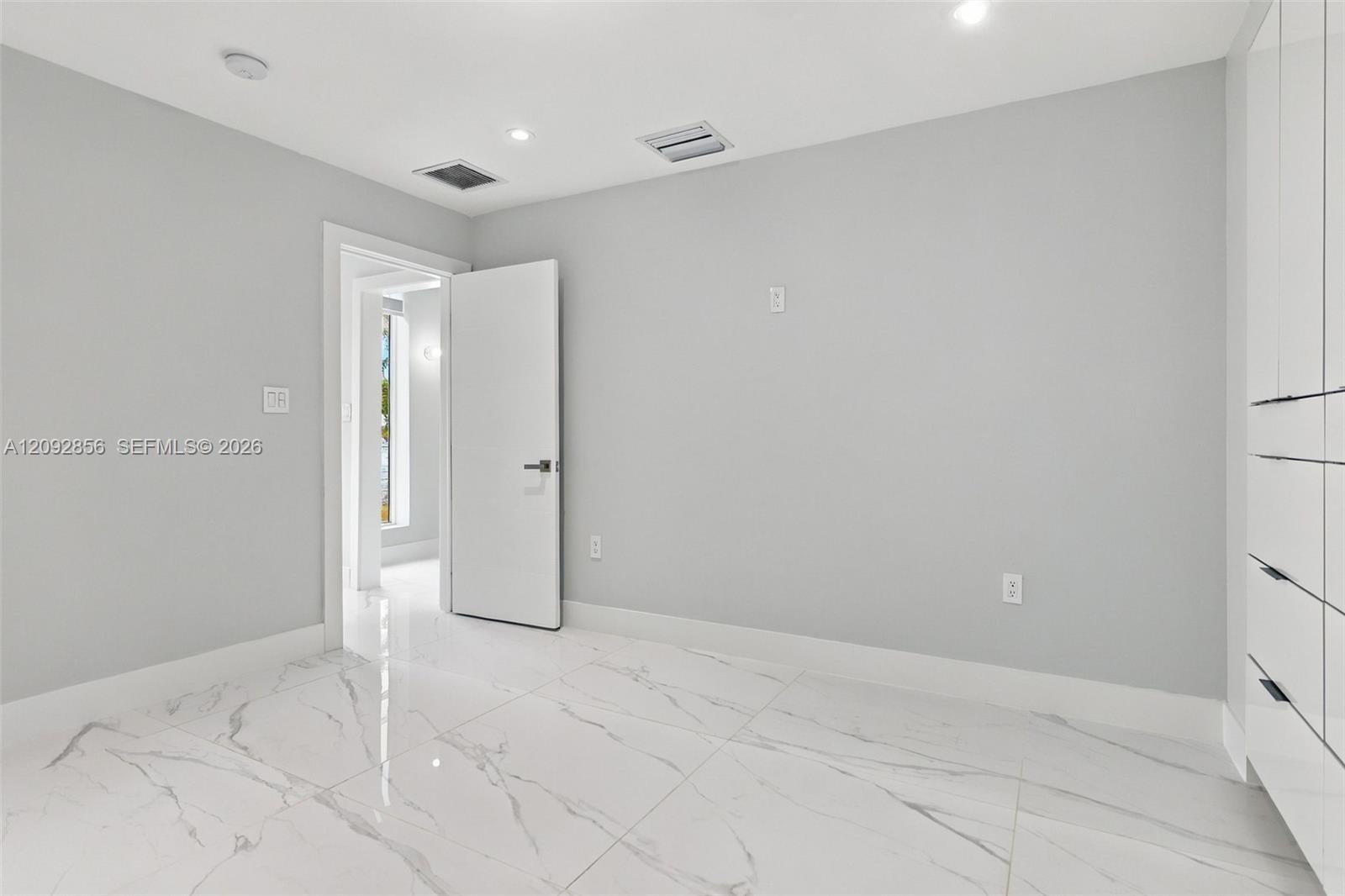 2nd bedroom - 1st floor - Neutral-toned room featuring large-format stone-patterned tile flooring, recessed ceiling lighting, and floor-to-ceiling built-in cabinetry with integrated hardware