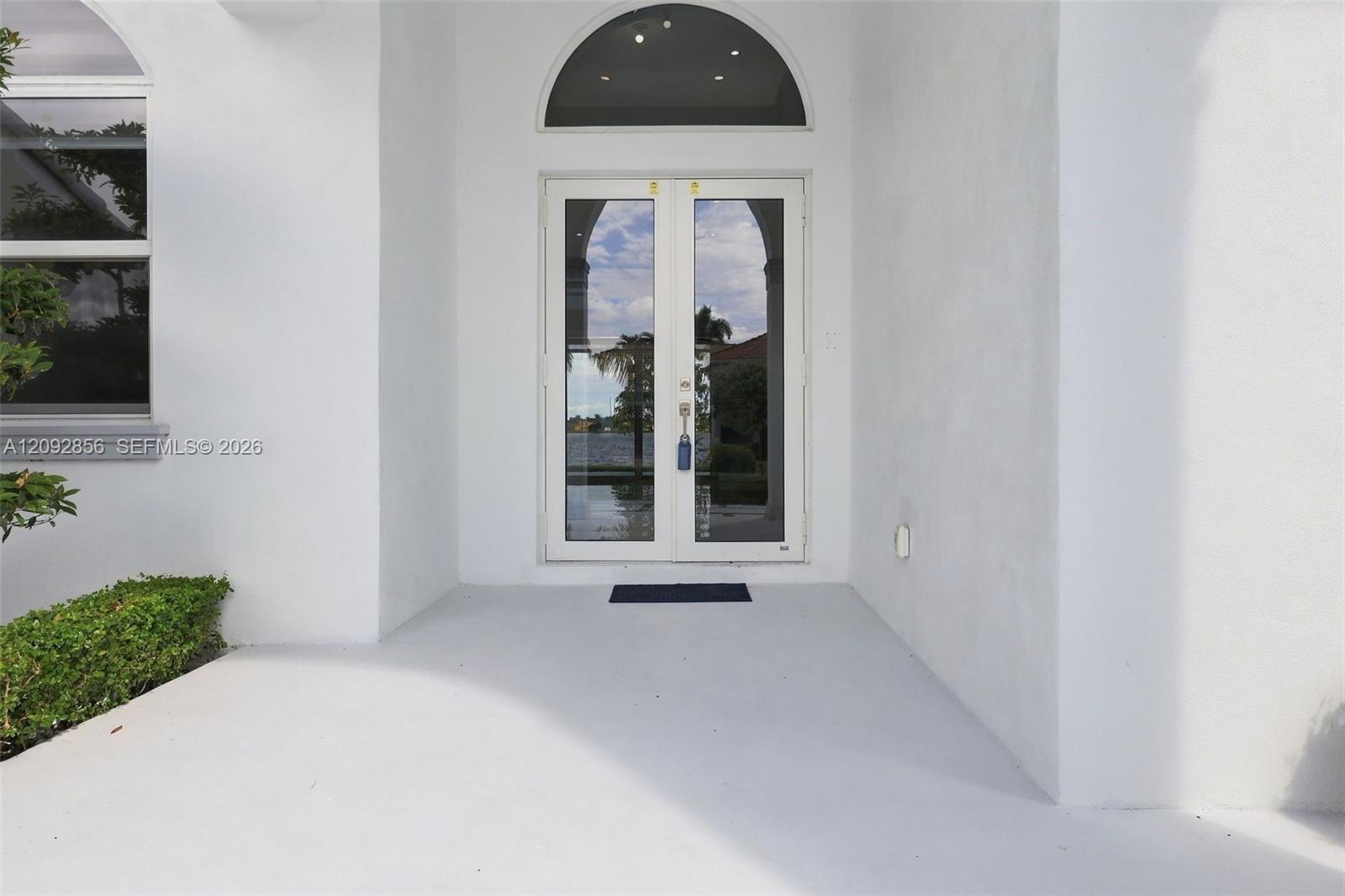 Entrance featuring double glass doors, a semi-circular transom window, and a concrete patio