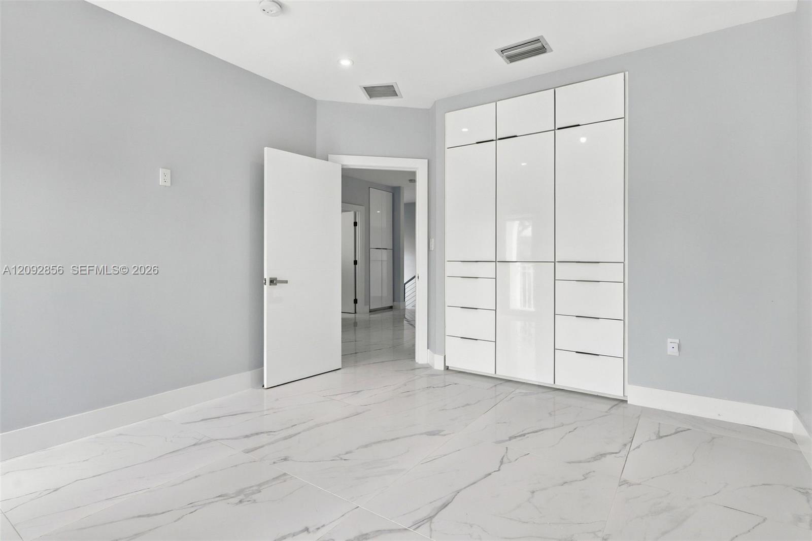 5th bedroom (balcony) - 2nd floor - Large-format tile flooring with marble-style veining and full-height built-in cabinetry featuring high-gloss, flat-panel doors and integrated hardware
