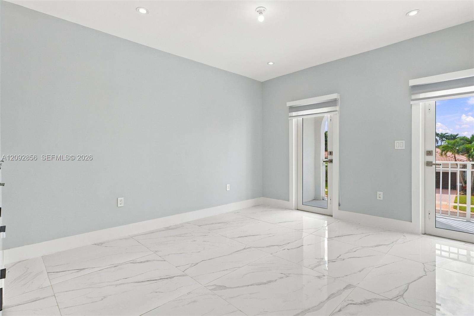 5th bedroom (balcony) - 2nd floor - Neutral-toned interior featuring large-format stone-patterned tile flooring, recessed lighting, and dual glass-paneled exterior doors with integrated shades