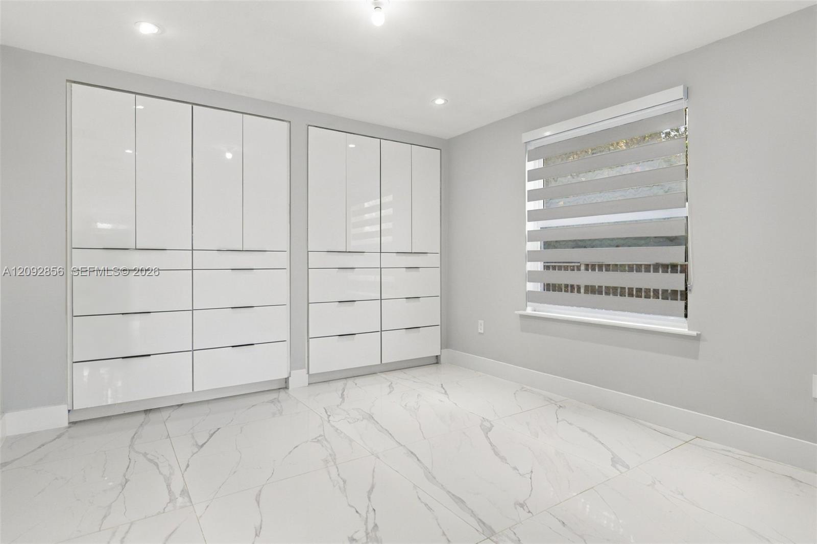 2nd bedroom - 1st floor - Glossy white built-in cabinetry featuring integrated drawers, large-format tile flooring with a veined pattern, and recessed ceiling lighting