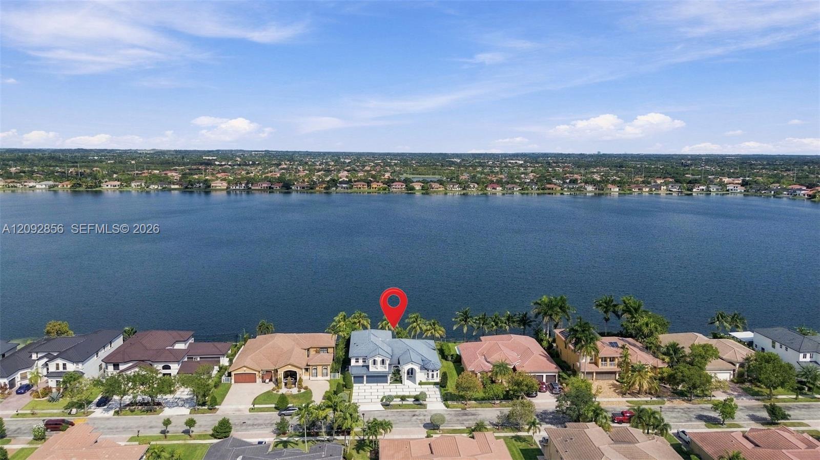 Waterfront property featuring direct water access, multi-story architectural design, paver driveway, and mature palm trees
