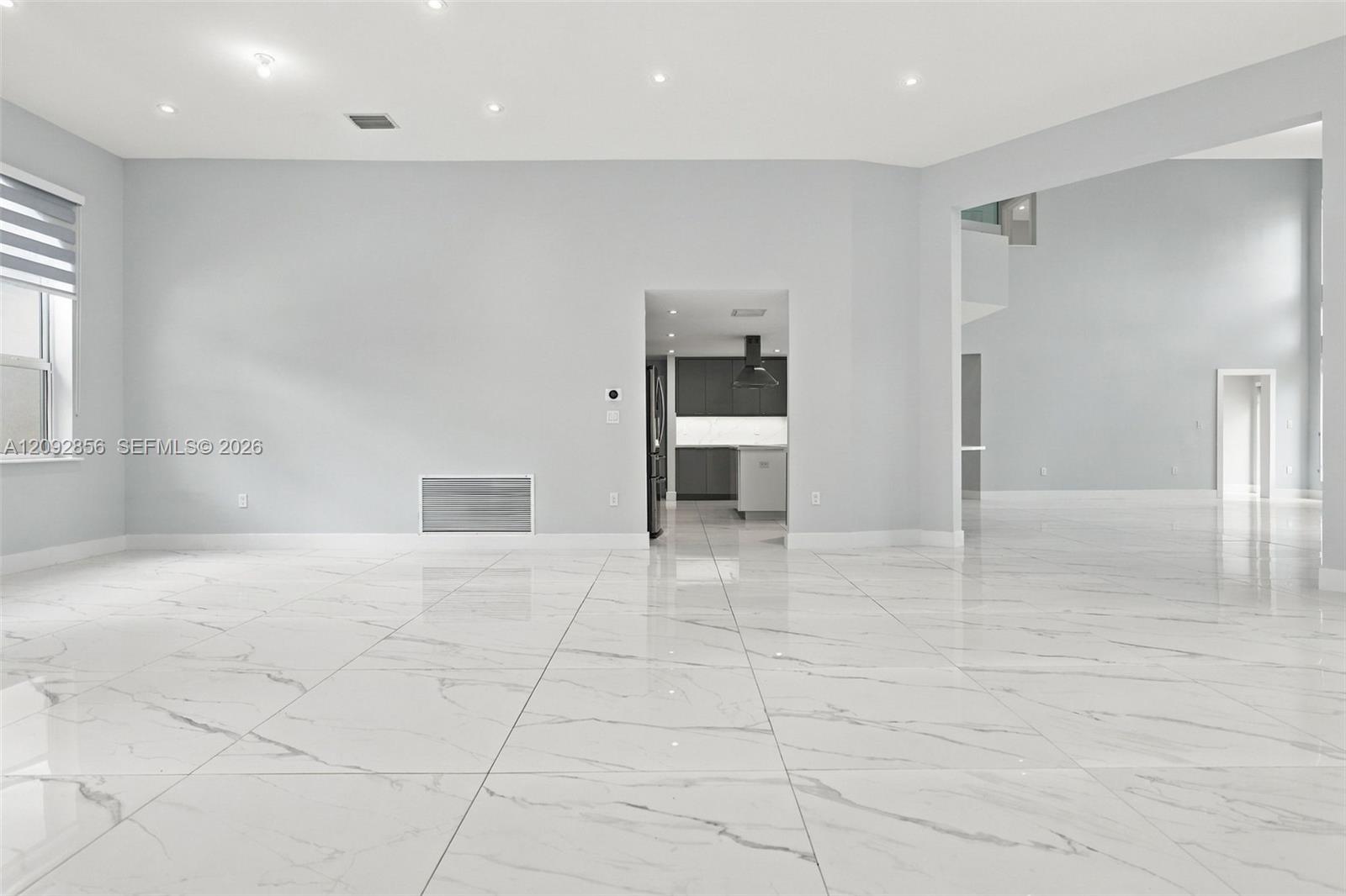 Open-concept interior featuring large-format stone-patterned tile flooring, recessed ceiling lighting, and neutral wall tones