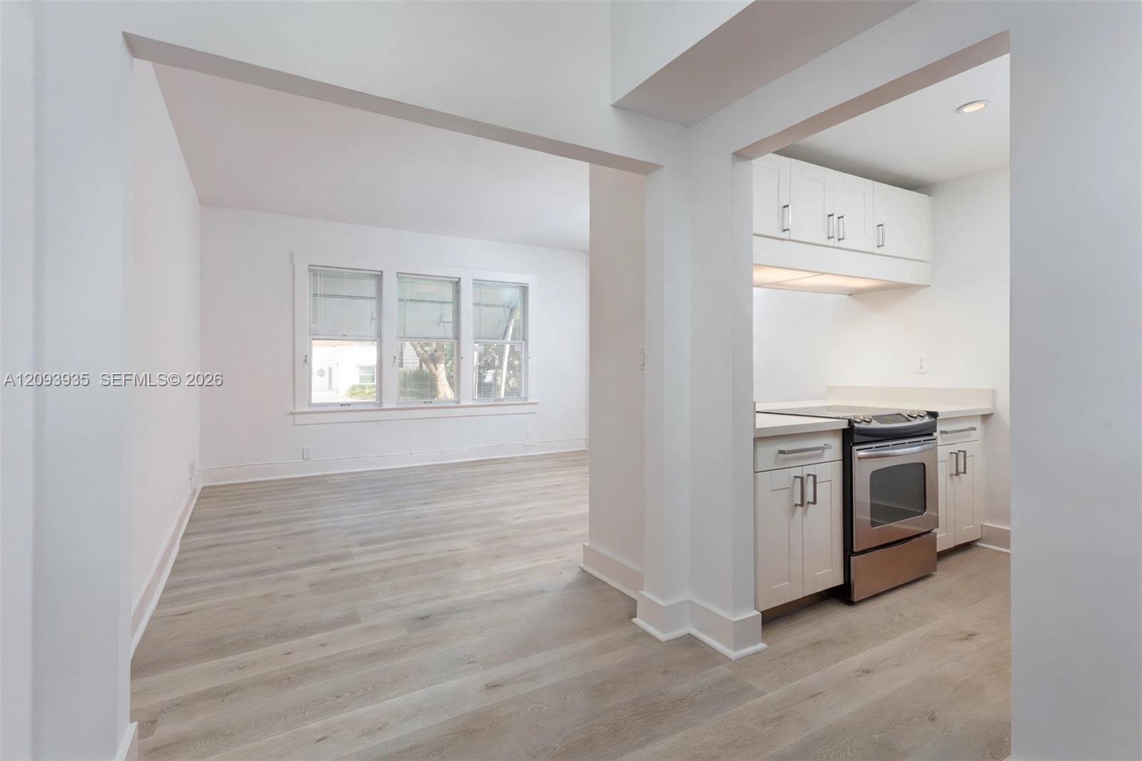 Wood-finish flooring throughout, white cabinetry with silver-tone hardware, and multiple windows with white trim Wood-finish flooring throughout, white cabinetry with silver-tone hardware, and multiple windows with white trim