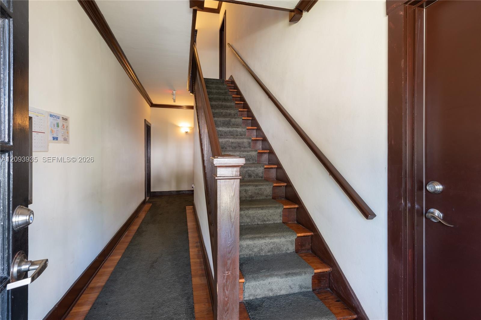 Entryway featuring dark-stained wood trim, wooden stairwell with a square newel post, and hardwood flooring Entryway featuring dark-stained wood trim, wooden stairwell with a square newel post, and hardwood flooring
