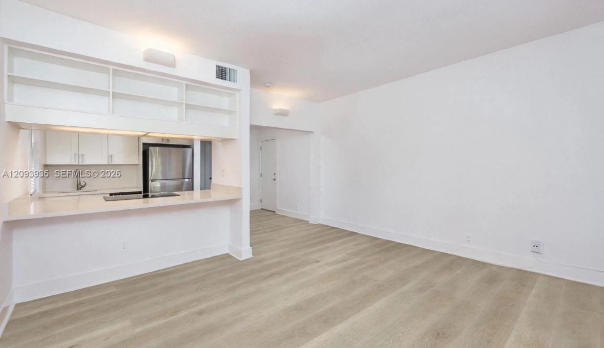 Kitchen area featuring white cabinetry, quartz-finish countertops, stainless steel appliances, and wood-finish flooring Kitchen area featuring white cabinetry, quartz-finish countertops, stainless steel appliances, and wood-finish flooring