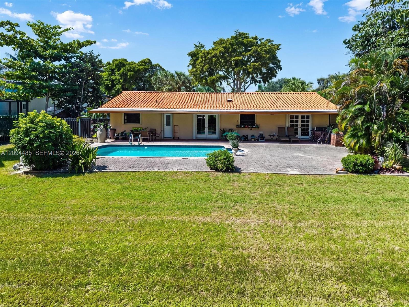 Exterior featuring a clay tile roof, rear swimming pool, paver patio, and lawn Exterior featuring a clay tile roof, rear swimming pool, paver patio, and lawn