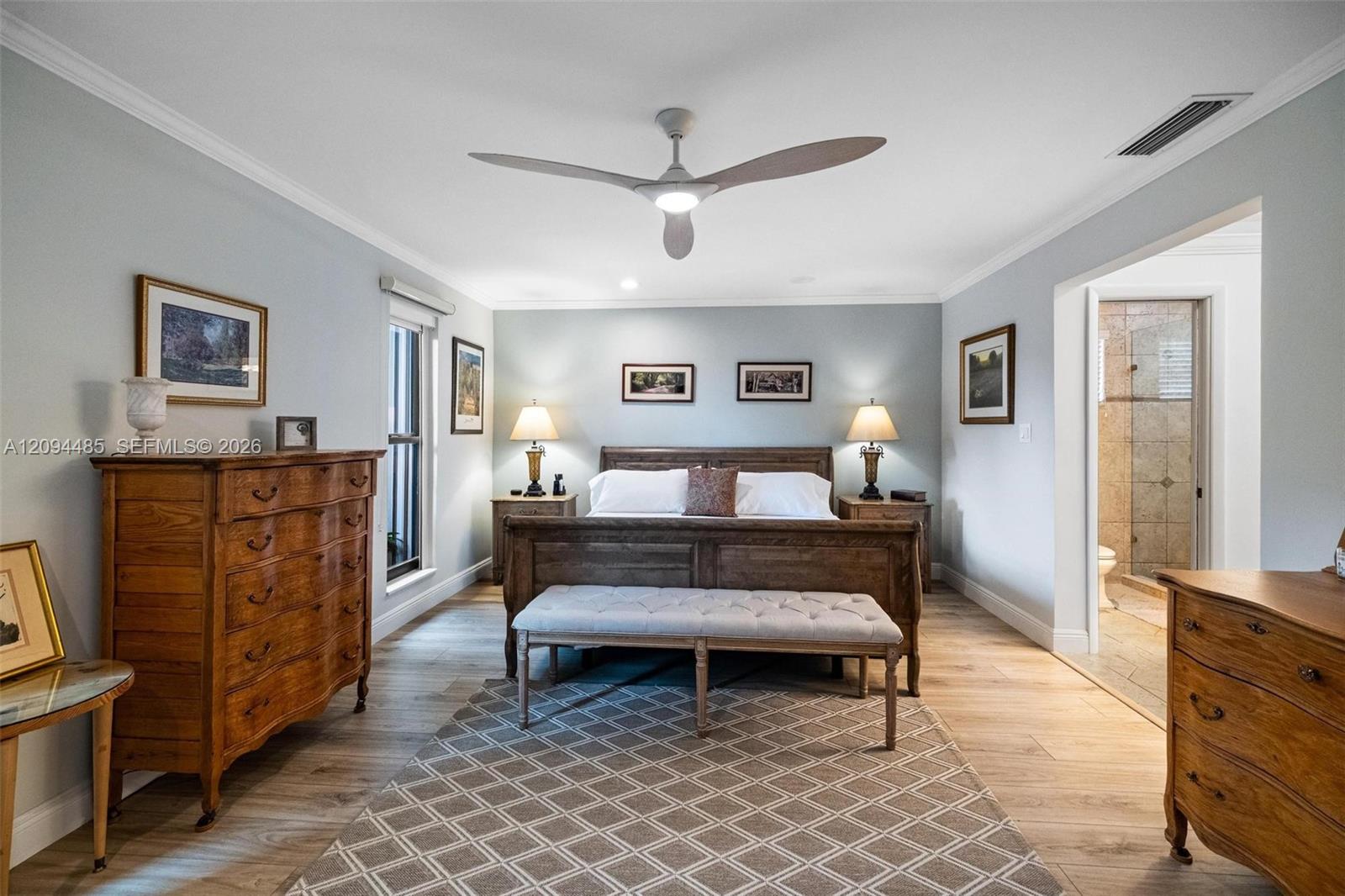Neutral-toned bedroom featuring wood-finish flooring, crown molding, and a modern ceiling fan