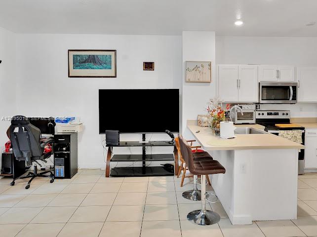 Kitchen featuring white cabinetry, solid-surface countertops, recessed lighting, and tile flooring Kitchen featuring white cabinetry, solid-surface countertops, recessed lighting, and tile flooring