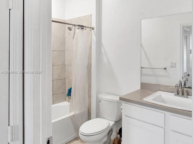 Bathroom featuring a white vanity cabinet, solid-surface countertop with an integrated basin, large wall-mounted mirror, and a tub-shower combination with light-toned wall tile