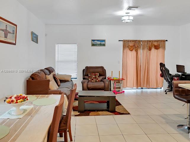 Open living area featuring neutral tile flooring, recessed lighting, and large sliding glass doors Open living area featuring neutral tile flooring, recessed lighting, and large sliding glass doors