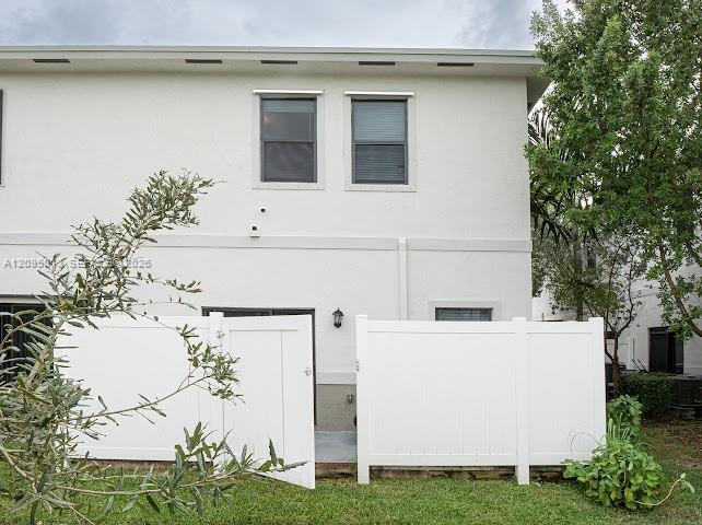 Stucco exterior featuring a white vinyl privacy fence and a rear patio