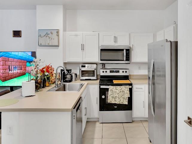 Kitchen featuring white cabinetry, stainless steel appliances, solid-surface countertops, and tile flooring Kitchen featuring white cabinetry, stainless steel appliances, solid-surface countertops, and tile flooring