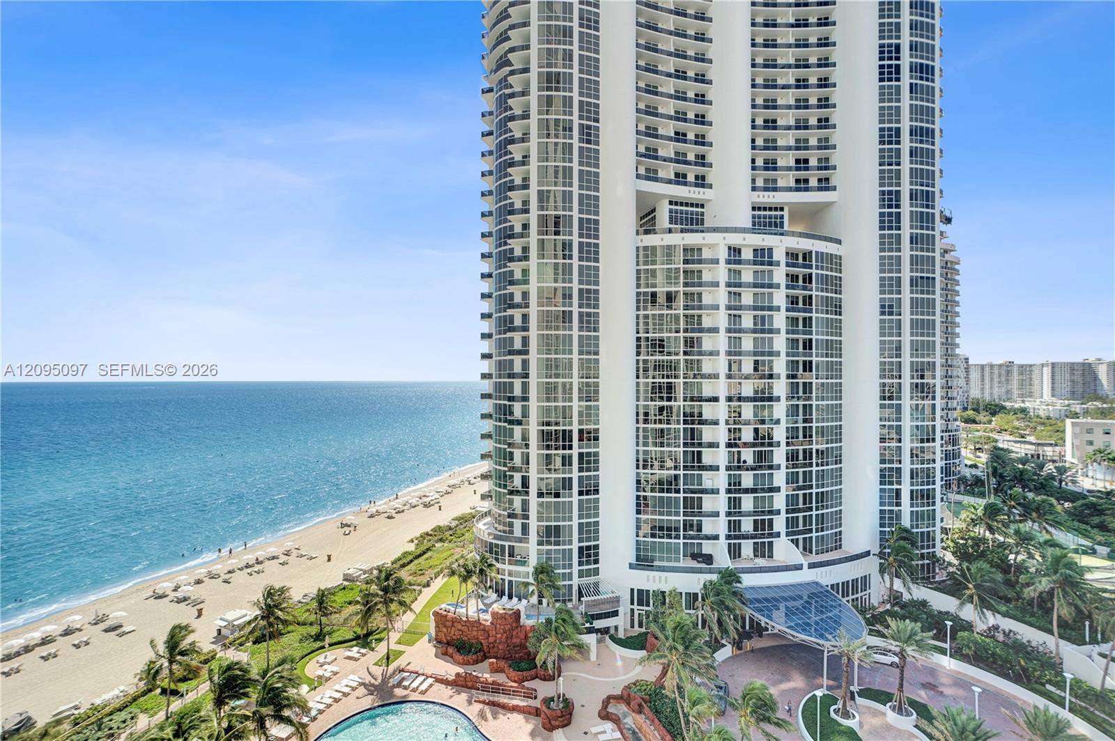 High-rise residential tower featuring floor-to-ceiling glass windows, wraparound balconies, an oceanfront location, a resort-style swimming pool, and a porte-cochre entry