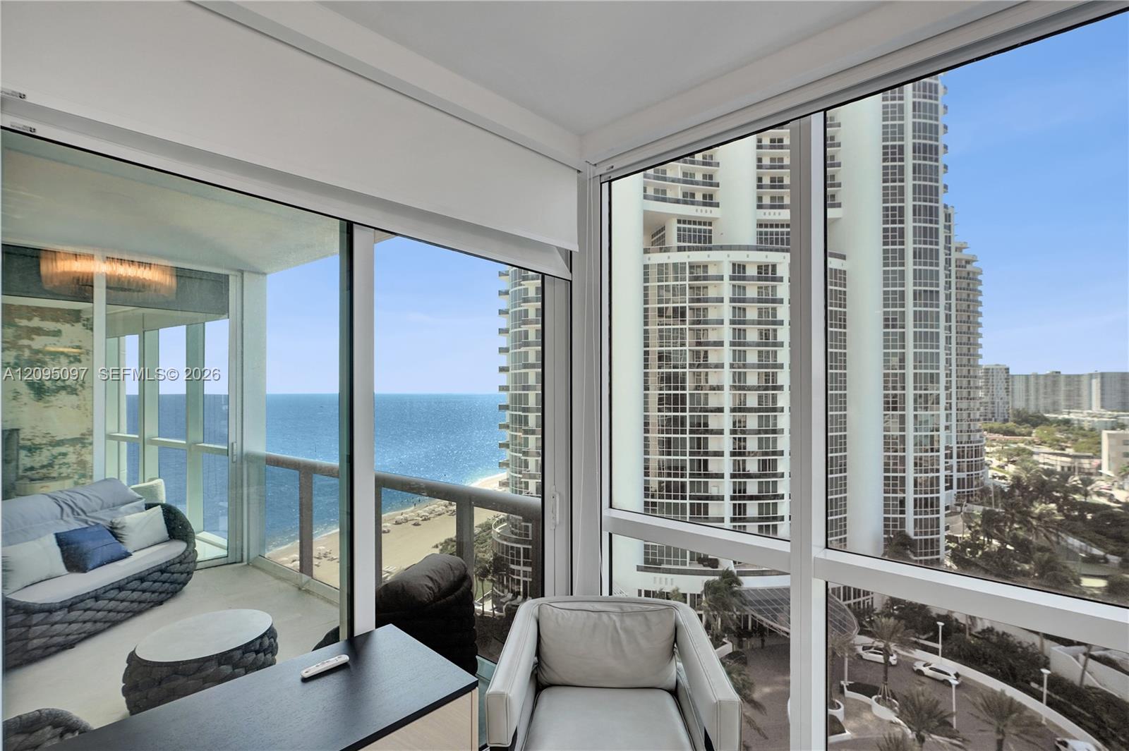 Floor-to-ceiling glass windows, expansive exterior balcony with glass railing, and coastal scenery