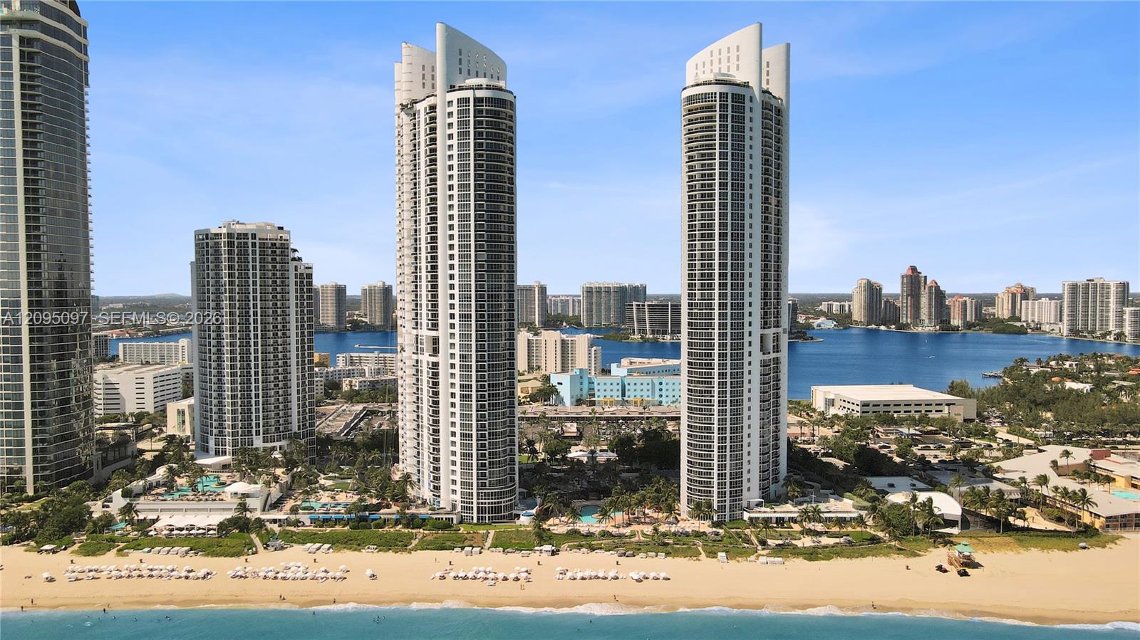 High-rise residential towers featuring glass-curtain facades, deep-set private balconies, and direct beachfront access with immediate proximity to coastal waterways