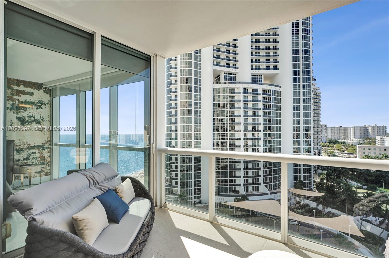 Private balcony featuring expansive floor-to-ceiling glass wall, sleek glass-panel railing, and durable tile flooring