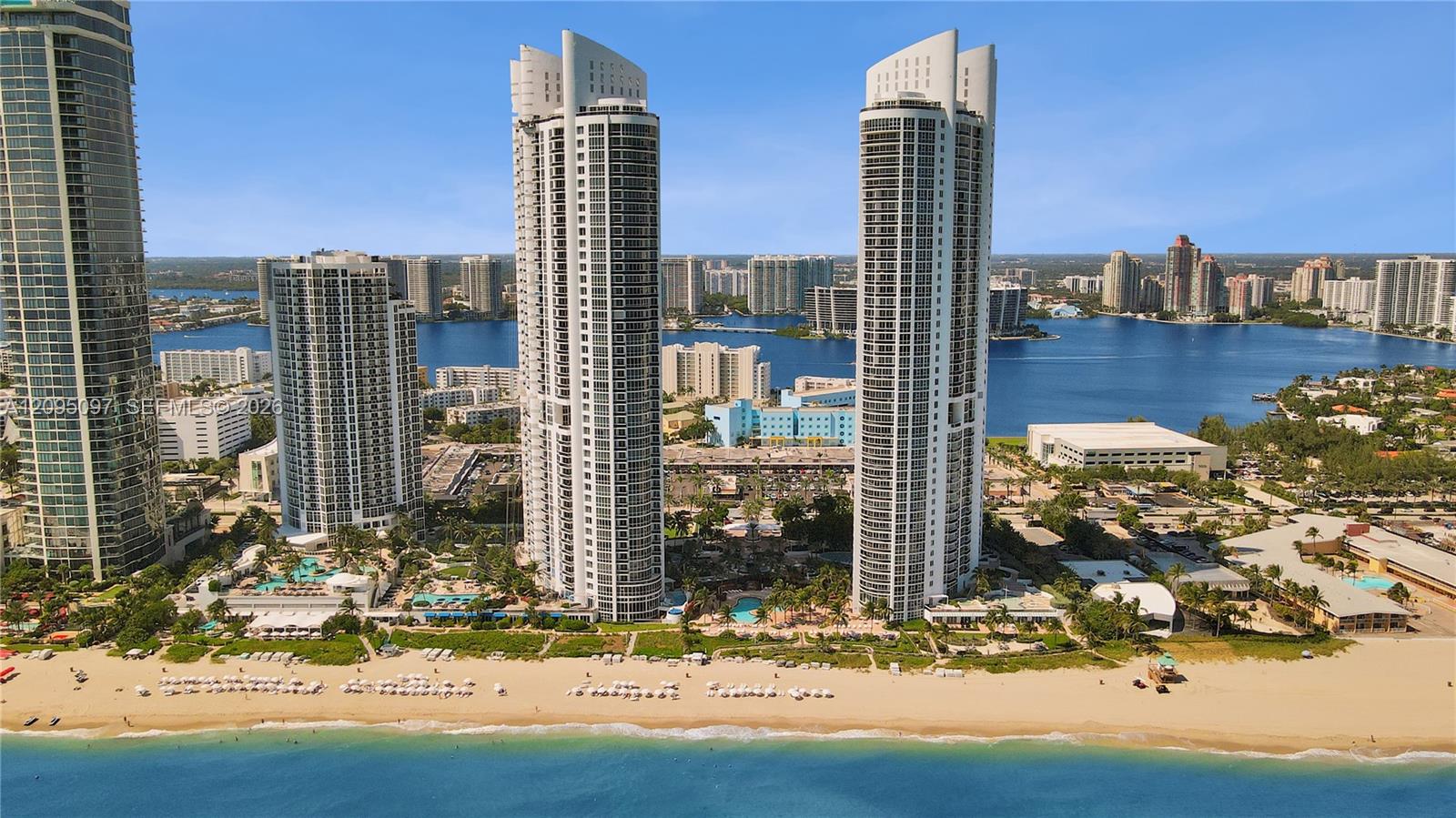 High-rise residential towers featuring glass-facade architecture, expansive balconies, direct waterfront access, and proximity to the coastline