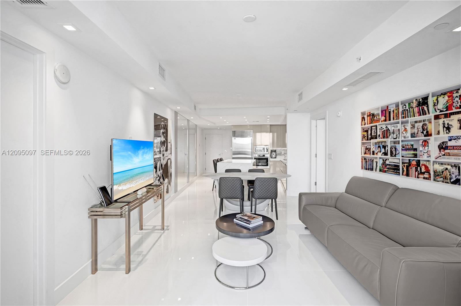 Open-concept interior featuring large-format polished tile flooring, recessed ceiling lighting, and custom built-in recessed shelving