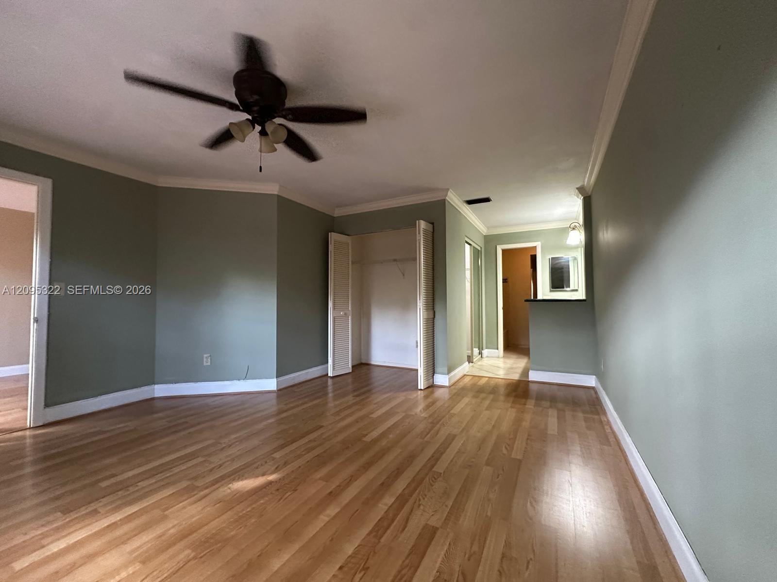 Wood-finish flooring, ceiling fan, crown molding, bi-fold closet doors, and a built-in counter surface