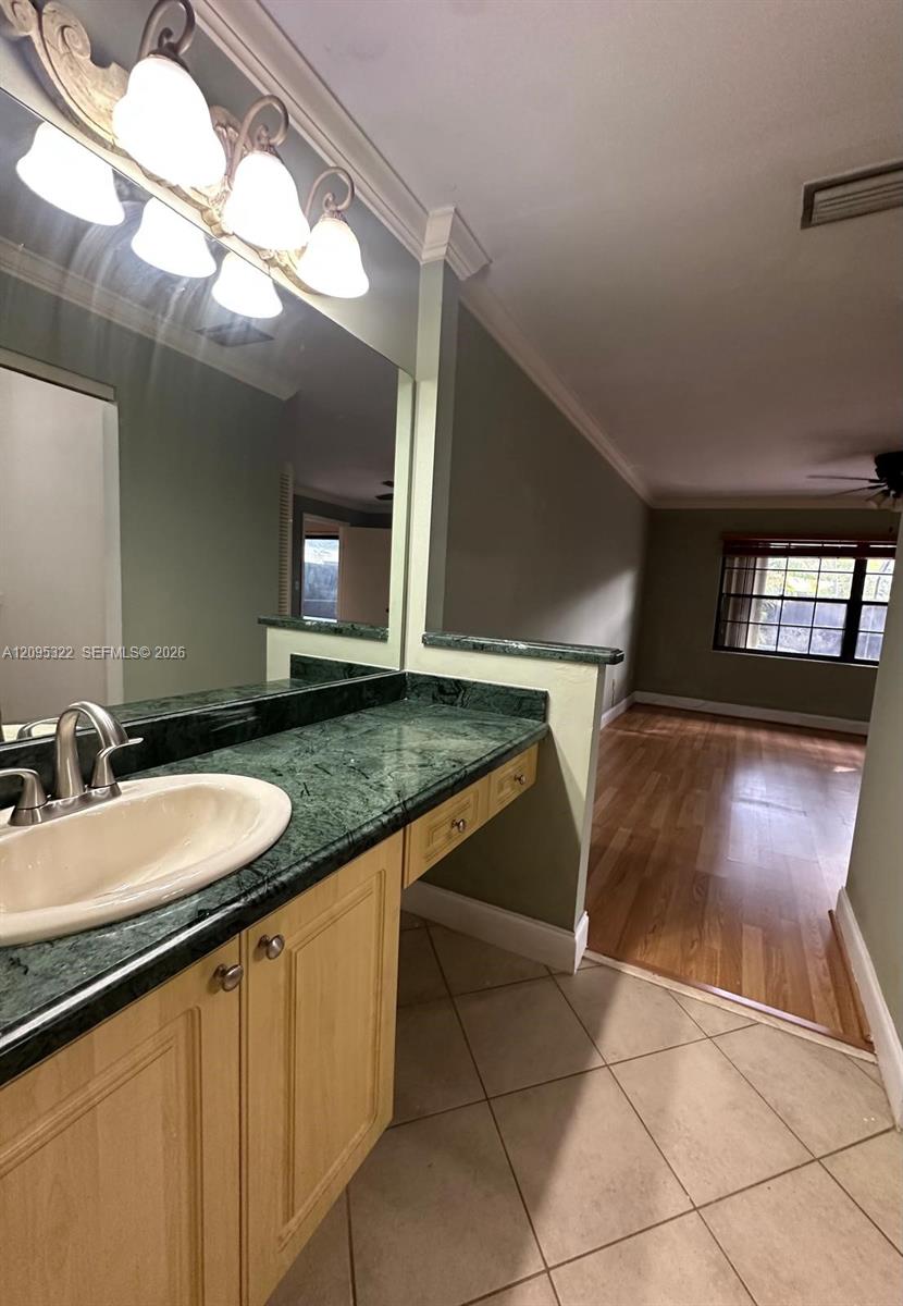 Vanity featuring stone-surfaced countertop, integrated oval basin, light-finish cabinetry, and crown molding