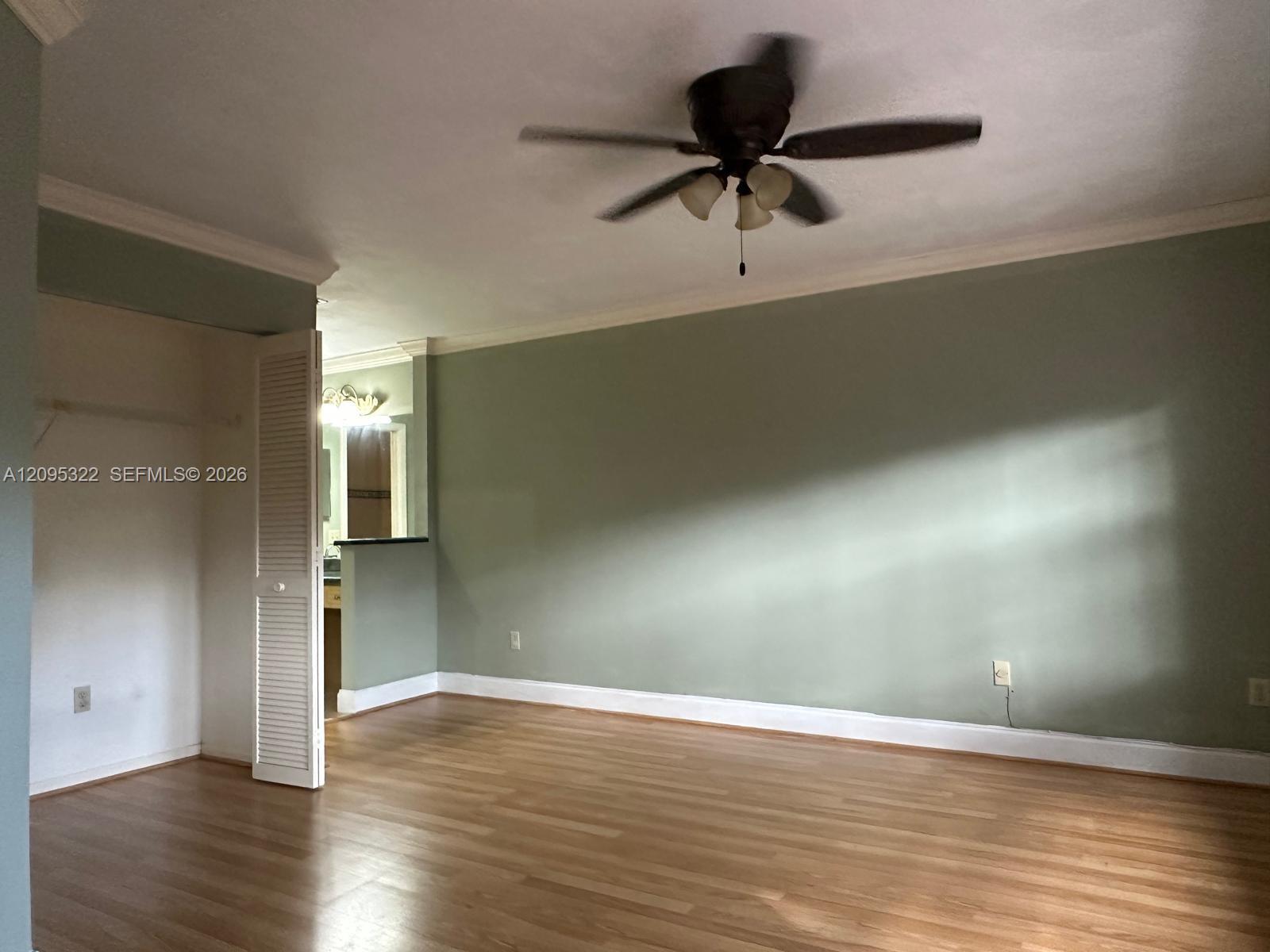 Wood-finish flooring, crown molding, and ceiling fan with integrated lighting