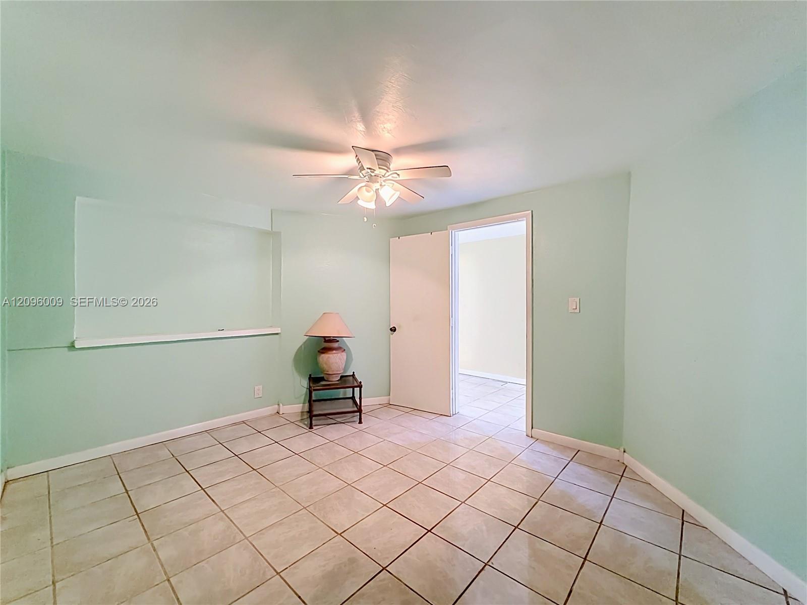 Neutral-toned tile flooring, recessed wall niche, and ceiling-mounted light fixture with fan