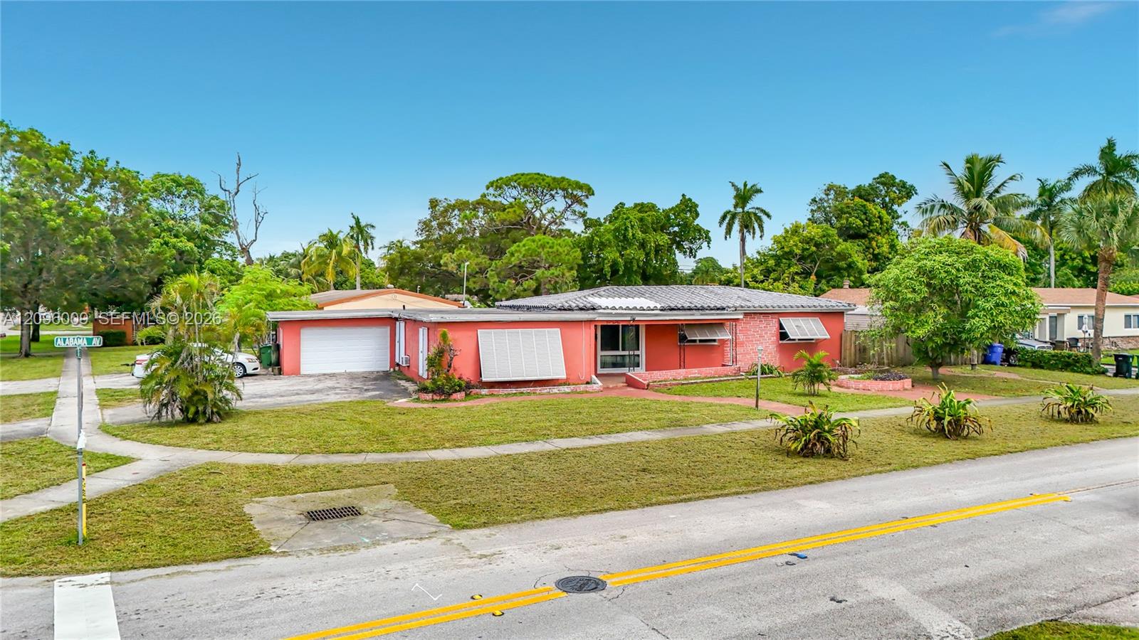 Single-story residence featuring a low-slope roof, stucco exterior, attached garage, and metal window awnings situated on a corner lot with mature landscaping
