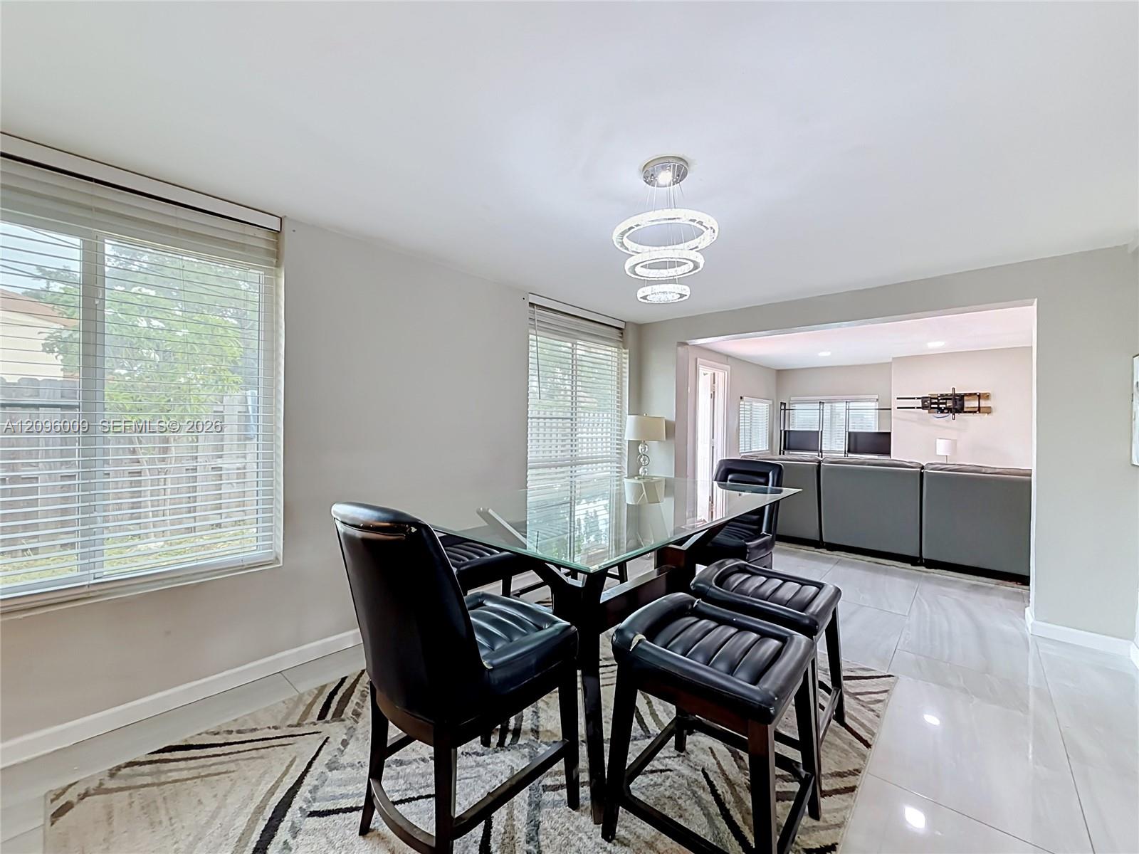 Large-format tile flooring, multi-tiered circular pendant lighting, and horizontal window blinds