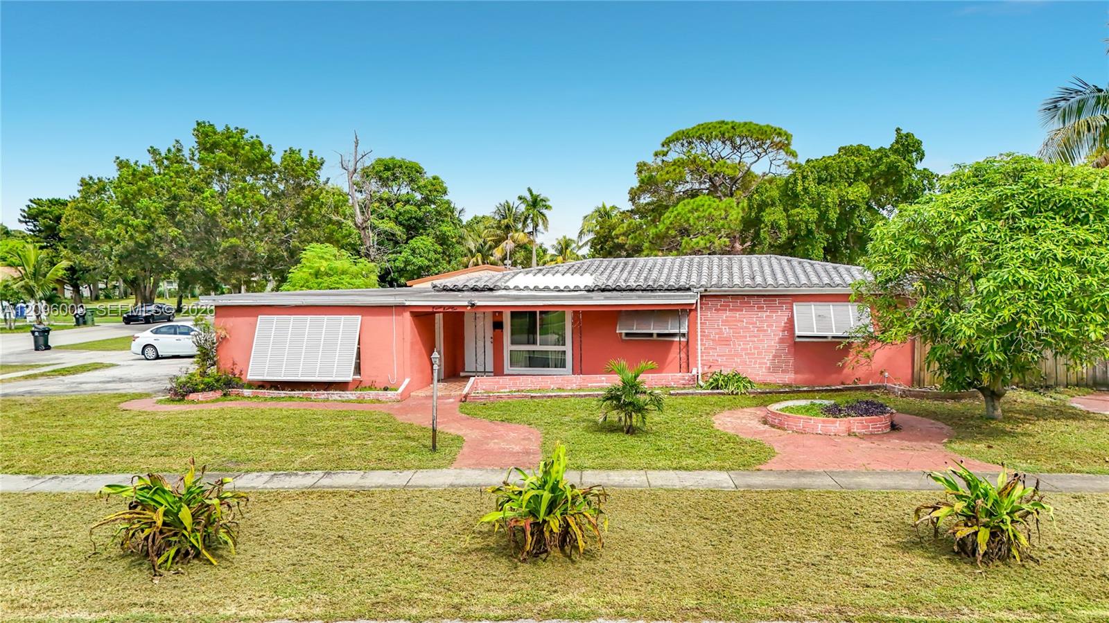 Single-story residence featuring a tile roof, brick exterior, metal window shutters, and a paved brick walkway