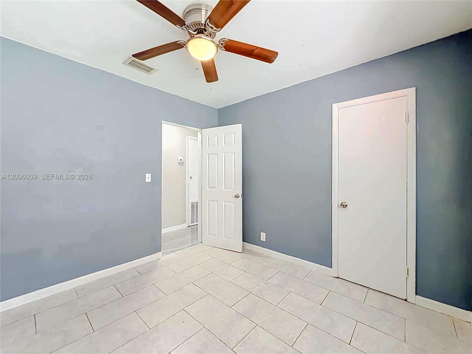 Interior space featuring ceramic tile flooring, a multi-blade ceiling fan with integrated lighting, and six-panel interior doors