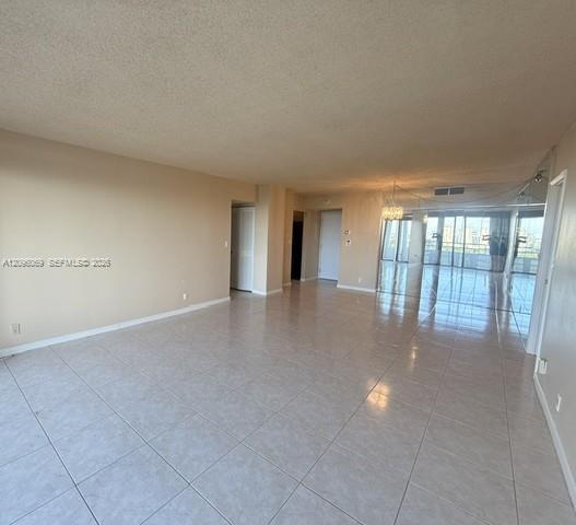 Open-concept interior featuring oversized tile flooring, full-length glass sliding doors, and a crystal-style chandelier