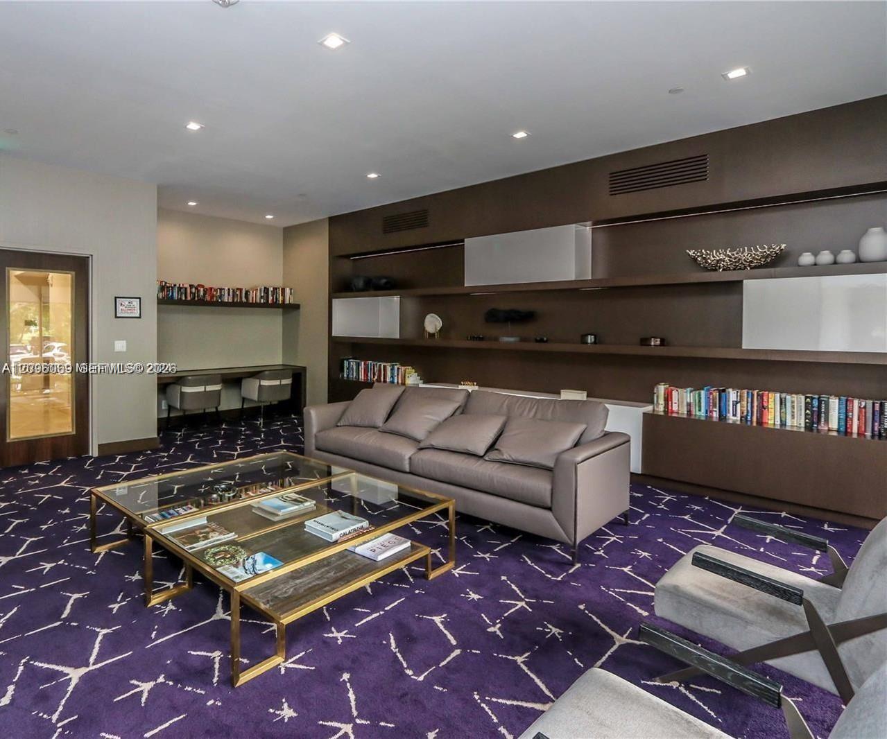 Custom wall-to-wall shelving with integrated cabinetry, built-in desk area, recessed lighting, and glass-paneled entry door