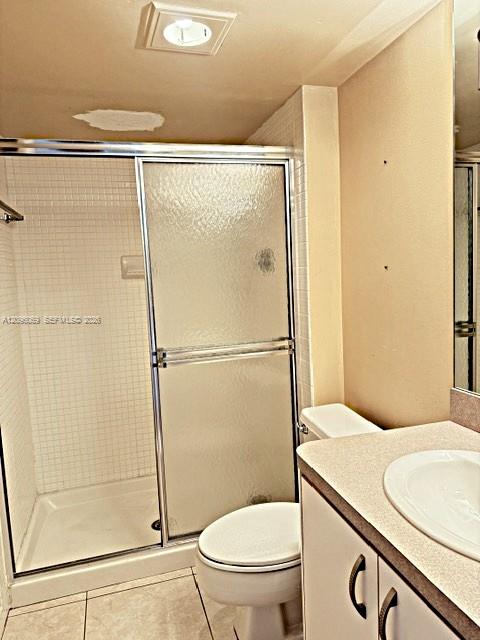 Shower enclosure with textured glass sliding doors and white tiled walls, paired with a vanity featuring a neutral countertop, integrated sink, and cabinetry with dark hardware