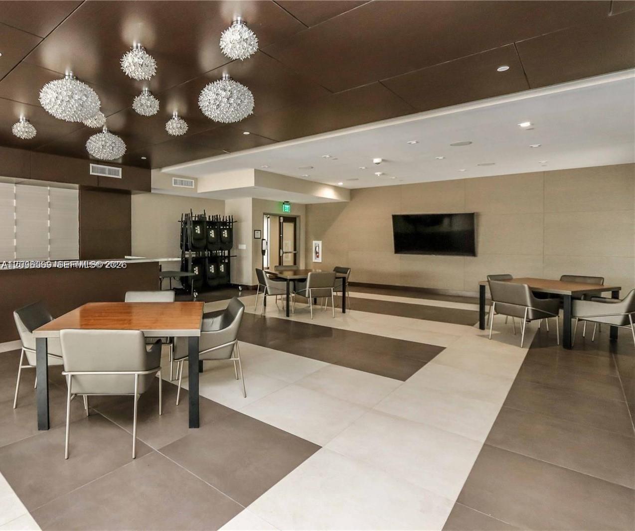 Large-format tile flooring, bronze-toned paneled ceiling, and multifaceted glass pendant light fixtures