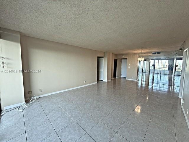 Open-concept interior featuring light-toned tile flooring, recessed lighting, and expansive floor-to-ceiling glass sliding doors