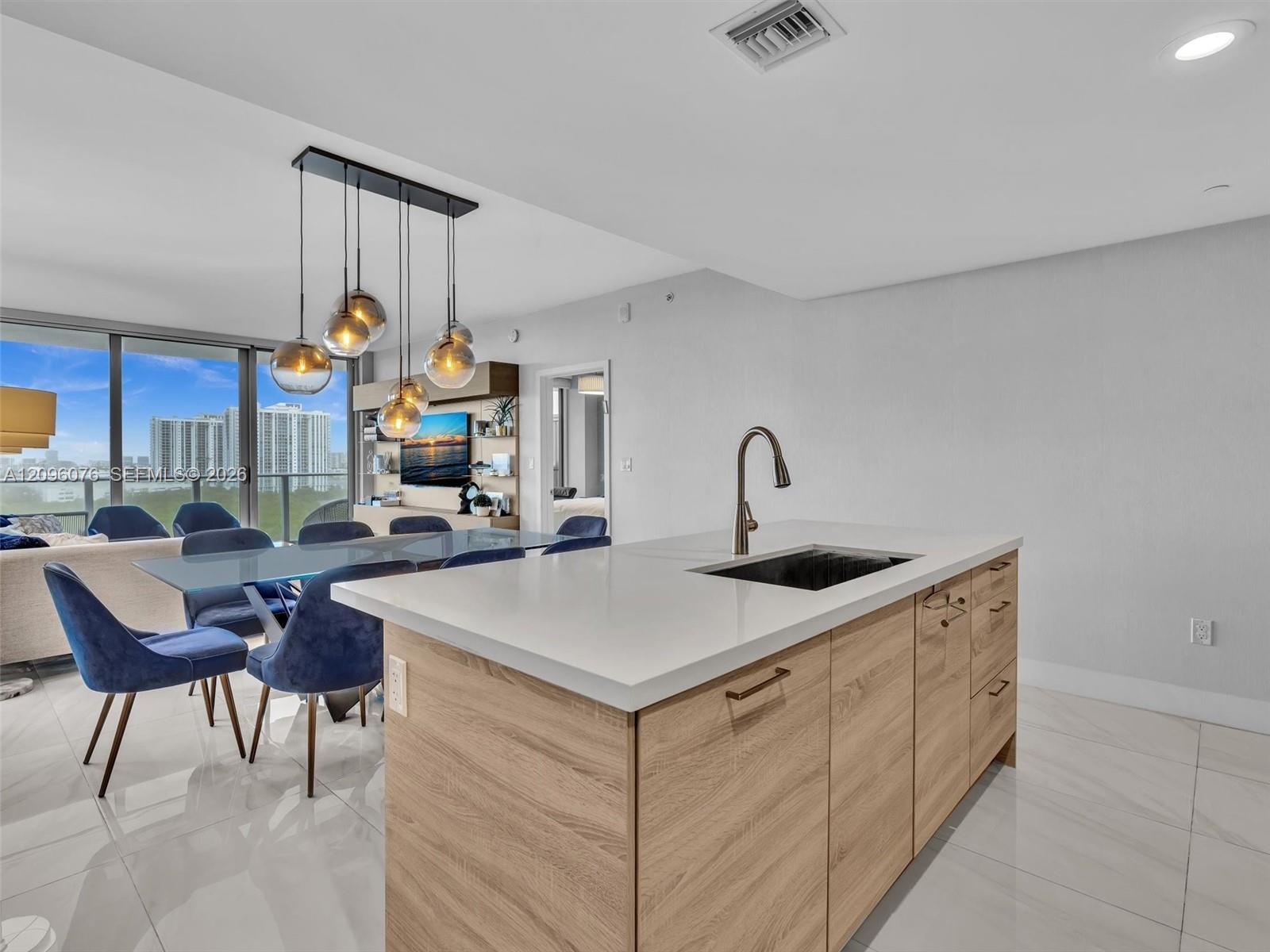 Kitchen island with wood-finish cabinetry, white countertop, and under-mount sink featuring a gooseneck faucet