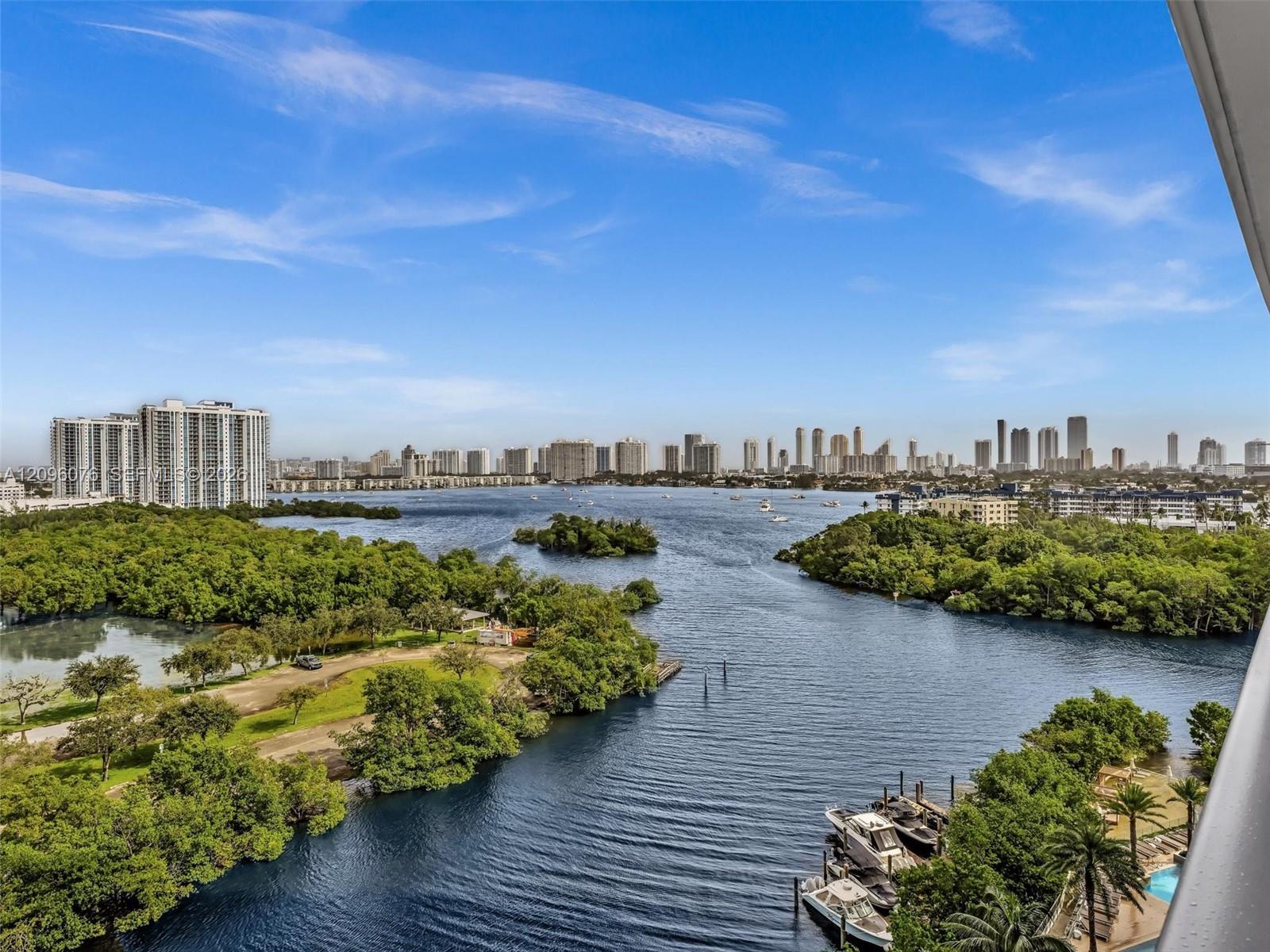 Panoramic water, island, and city skyline scenery featuring a waterway, mature vegetation, and multiple boat docks