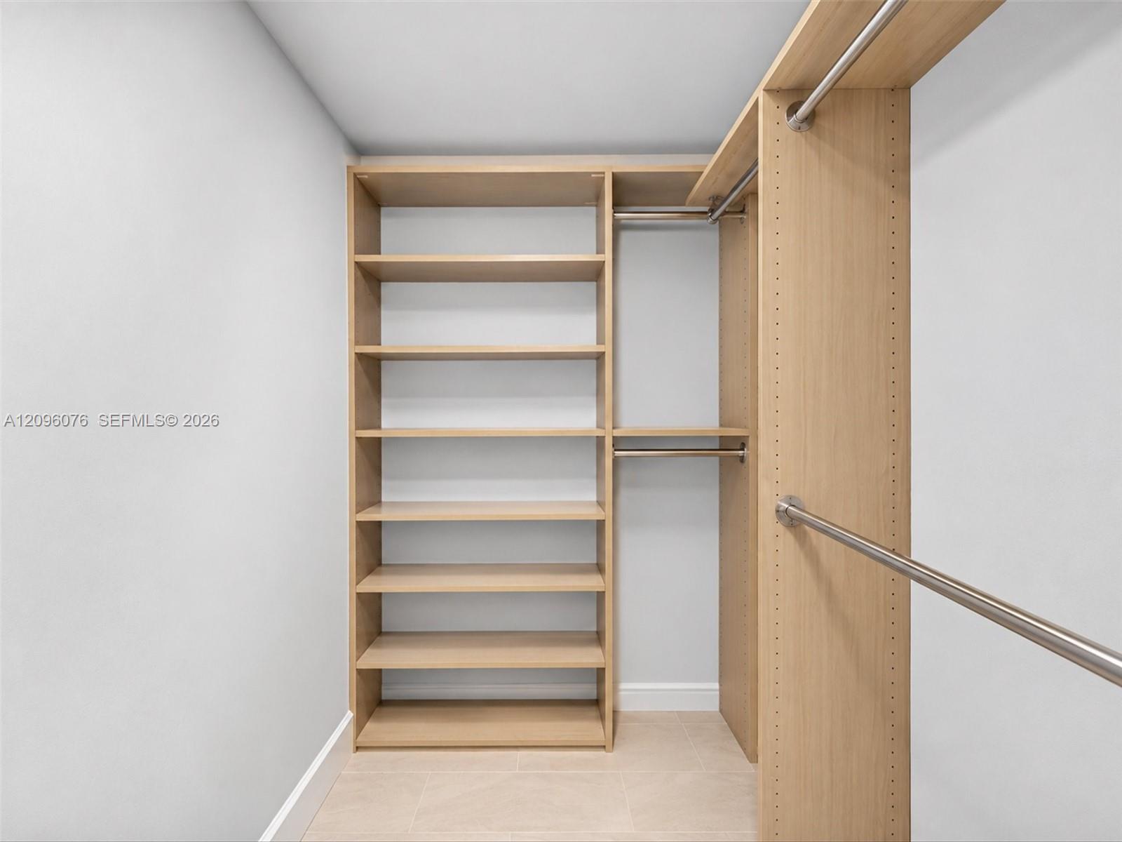 Custom built-in storage featuring light wood-finish shelving, integrated metallic hanging rods, and adjustable hardware