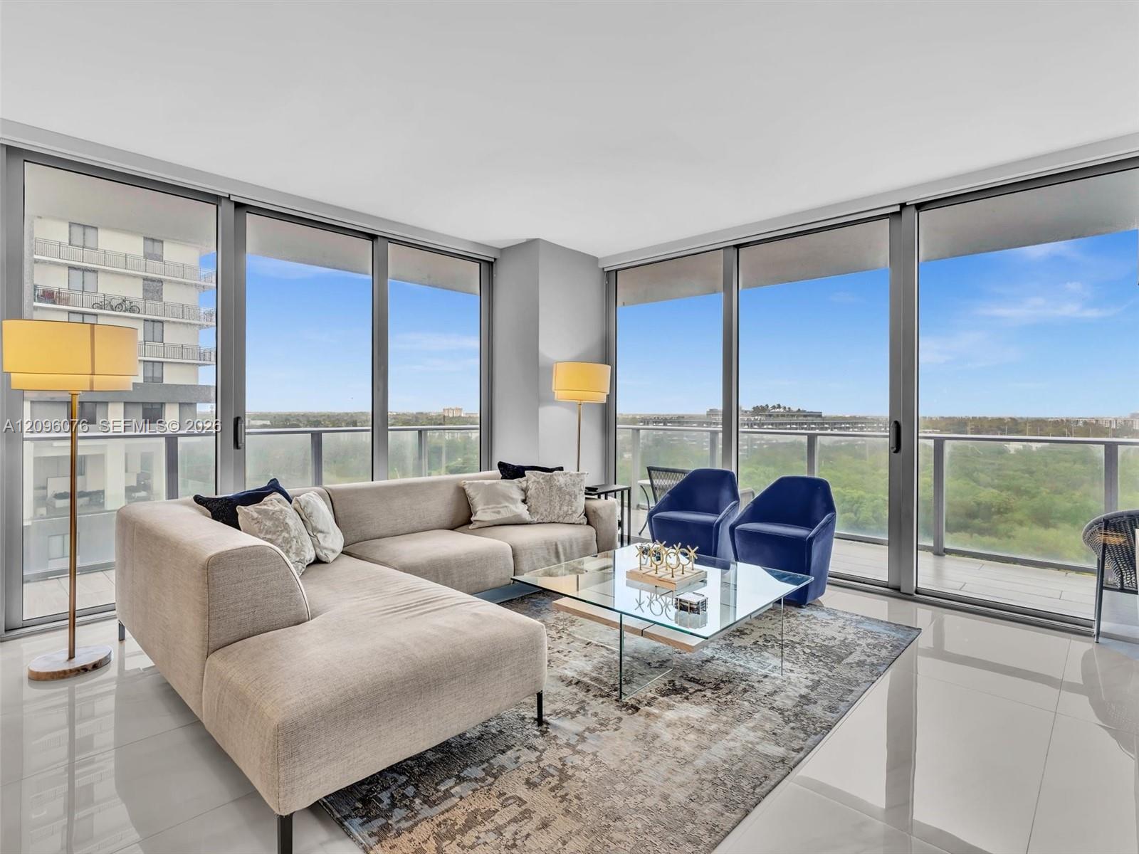 Floor-to-ceiling windows, polished tile flooring, and a wrap-around balcony with metal railing
