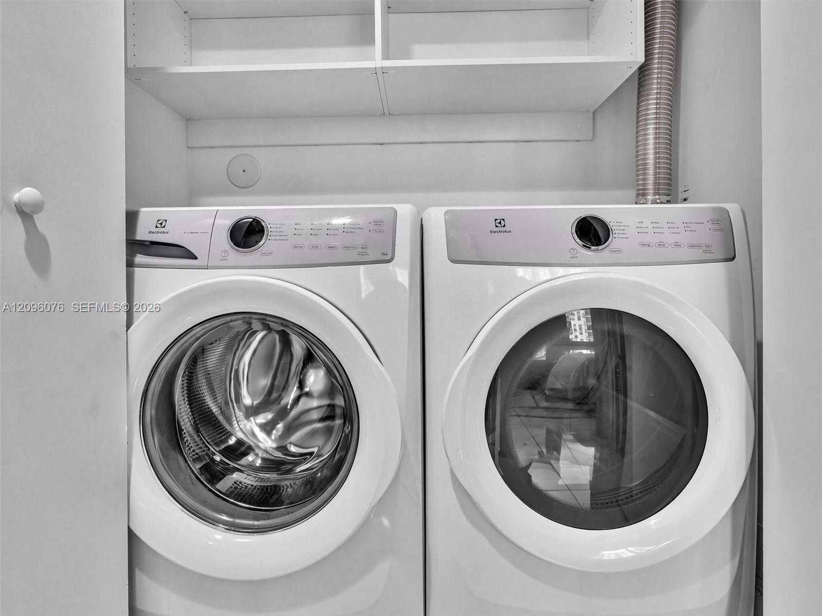 Laundry area featuring built-in white shelving and side-by-side front-loading appliances