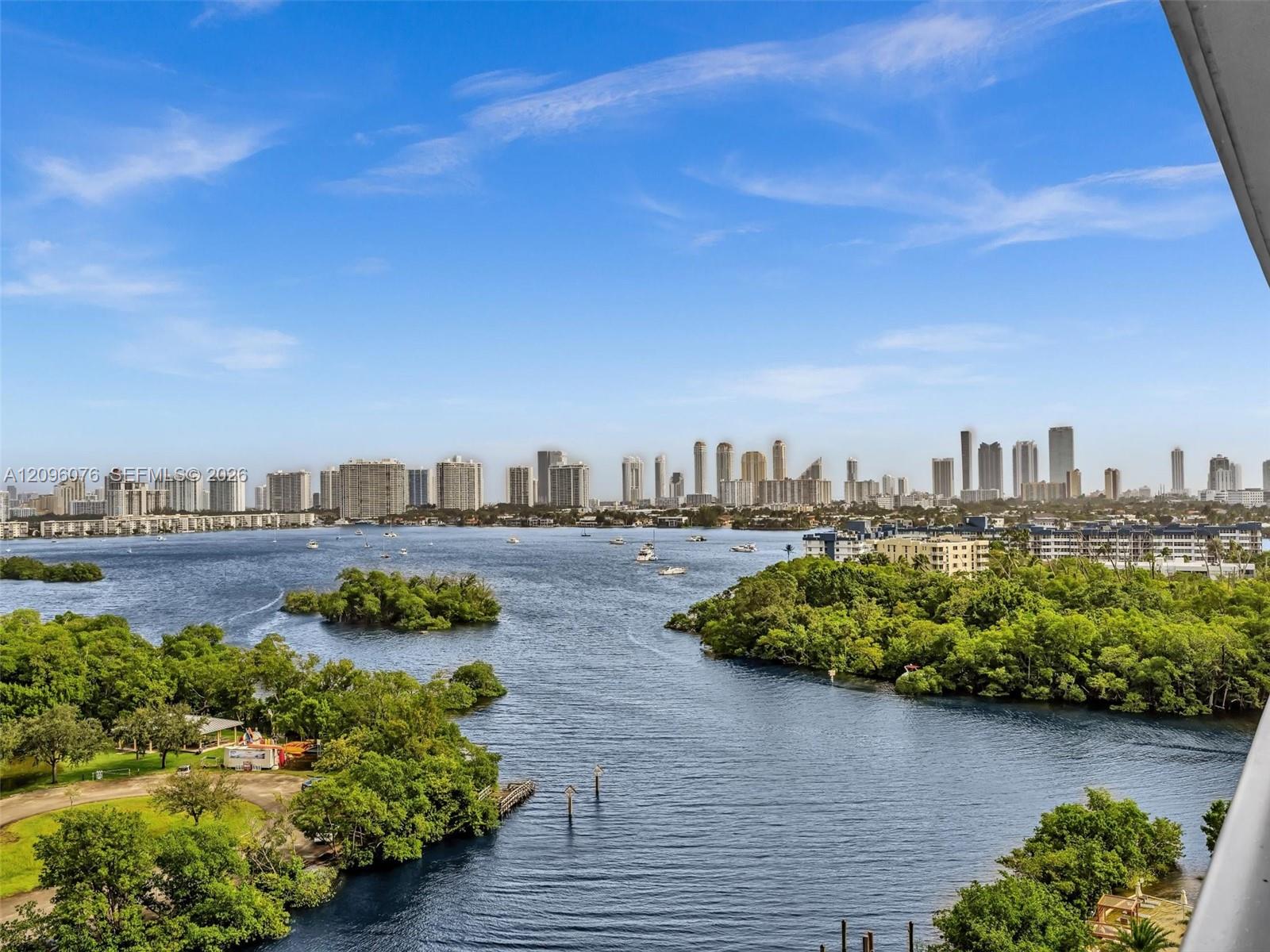 Panoramic skyline and expansive water scenery featuring a wide waterway, coastal vegetation, and urban high-rise buildings