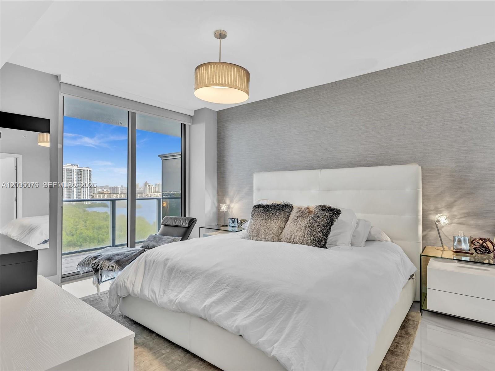 Floor-to-ceiling glass windows, textured grey accent wall, drum shade pendant lighting, polished tile flooring, and integrated balcony access