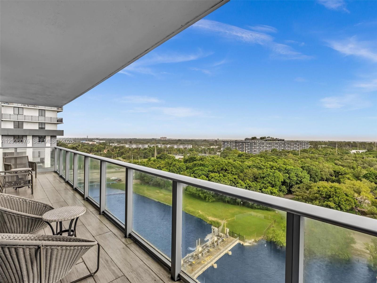 Covered balcony featuring wood-finish tile flooring, glass panel railings, and metal framing