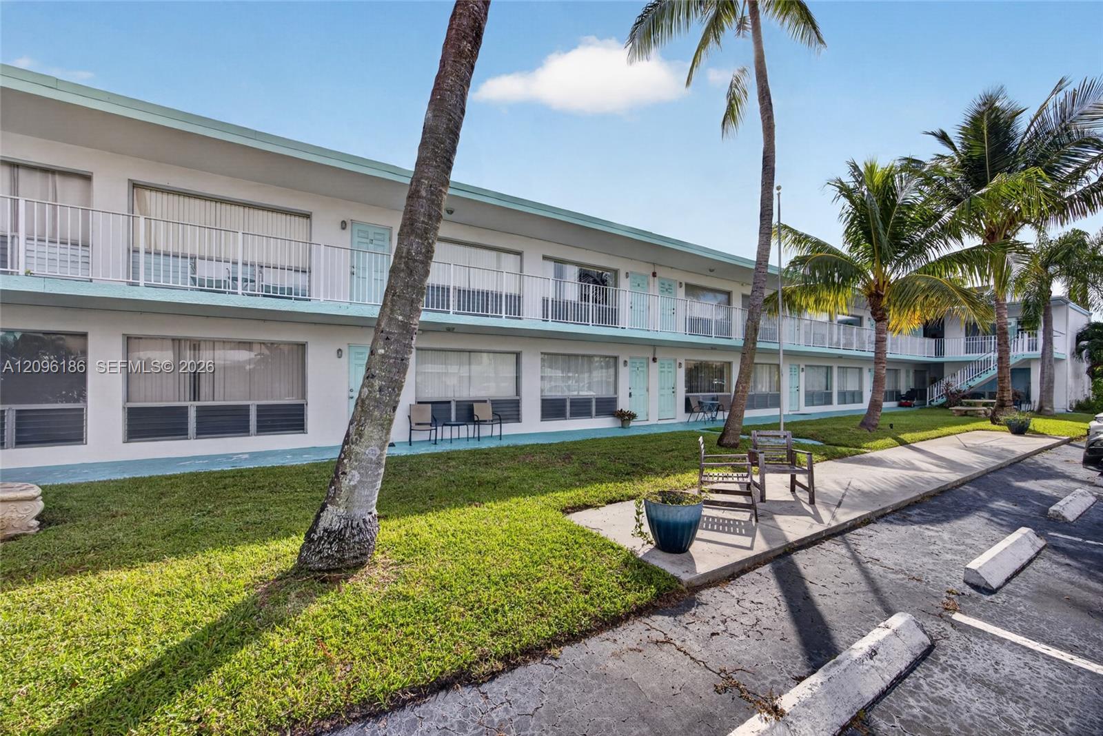 Mid-century exterior featuring a two-story design, private upper-level balconies with metal railings, expansive sliding glass windows, and mature palm trees