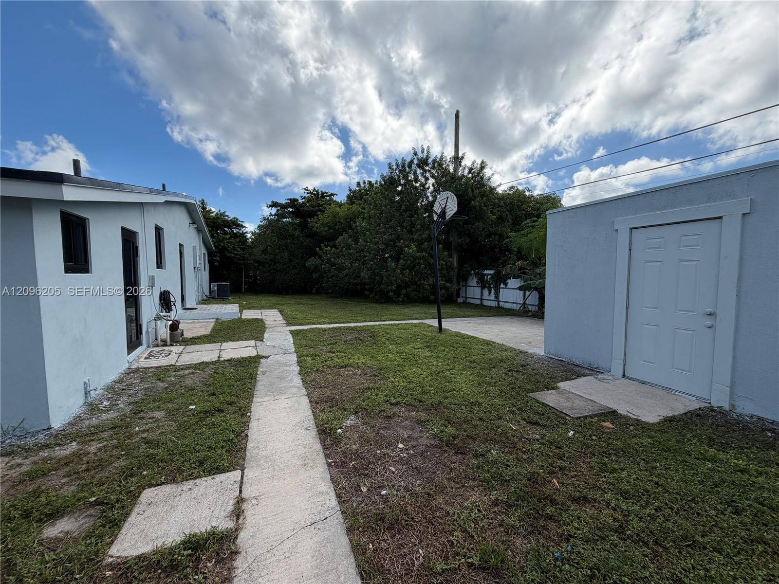 Backyard featuring a concrete walkway, detached storage structure, and lawn area