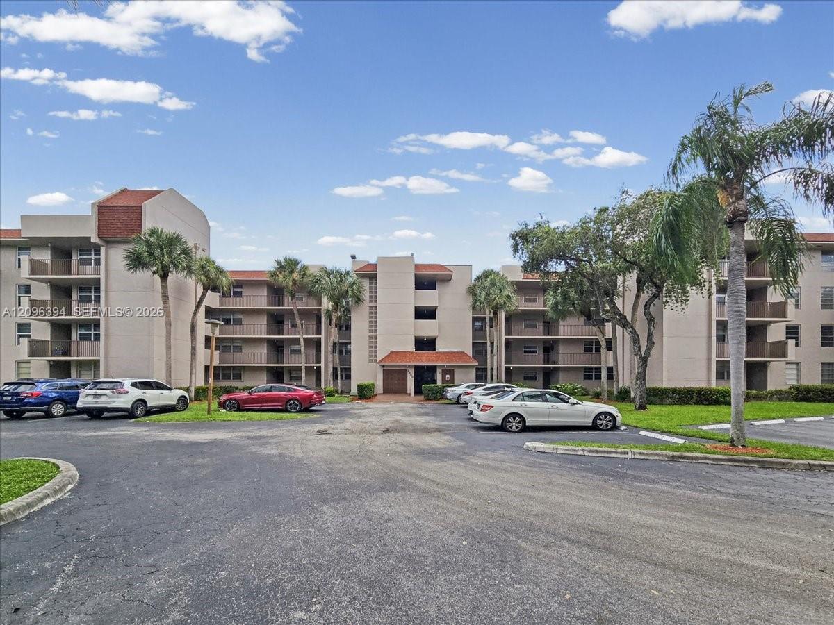 Multi-story building exterior featuring a tiled roof, stucco facade, and recessed private balconies