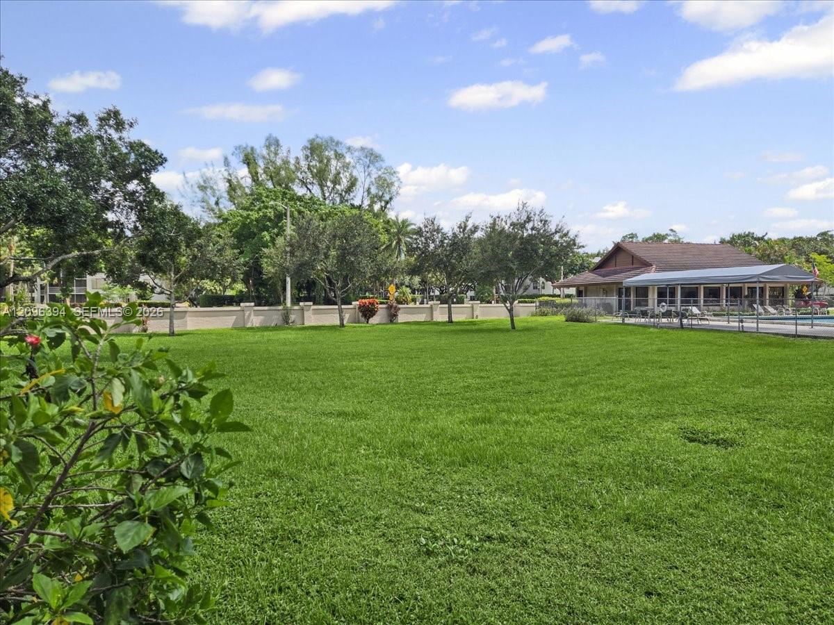 Expansive lawn featuring perimeter wall enclosure, mature landscaping, and a covered pavilion structure